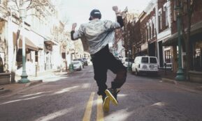 man jumping on the middle of the street during daytime