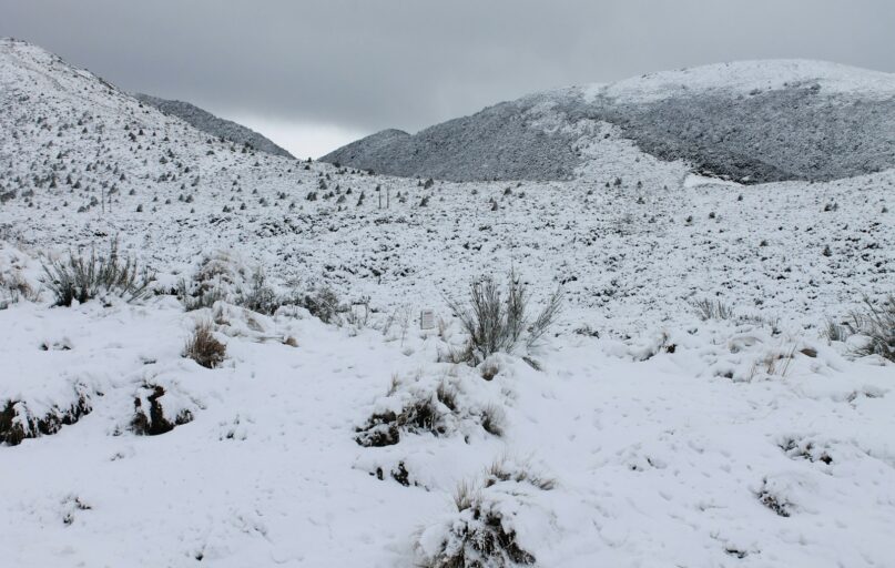 a snow covered field with mountains in the background