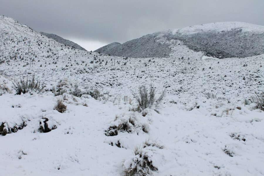 a snow covered field with mountains in the background