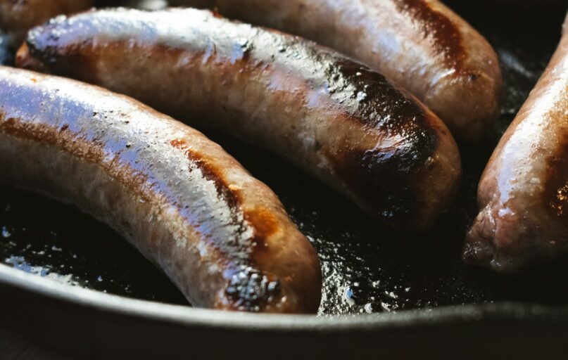 a group of hot dogs cooking in a frying pan