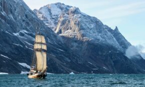 brown and white boat on sea near mountain during daytime