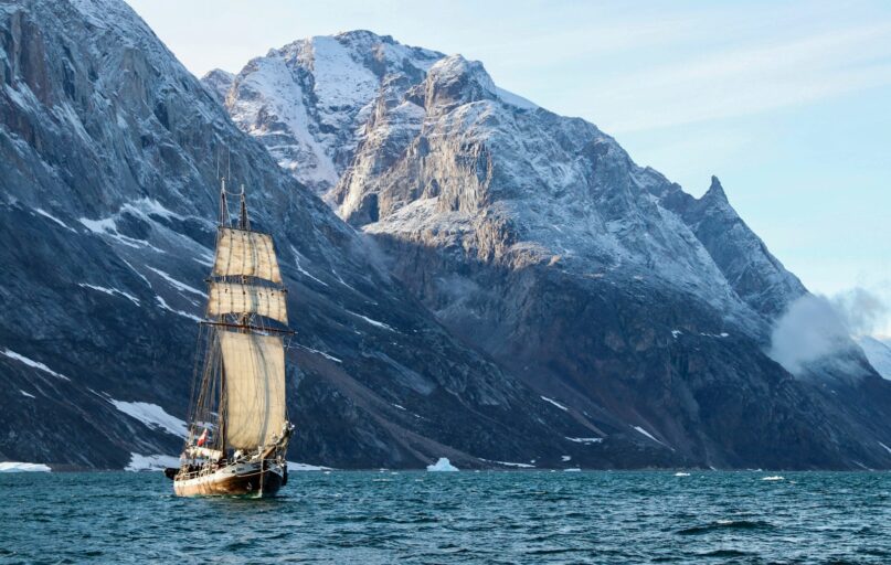 brown and white boat on sea near mountain during daytime