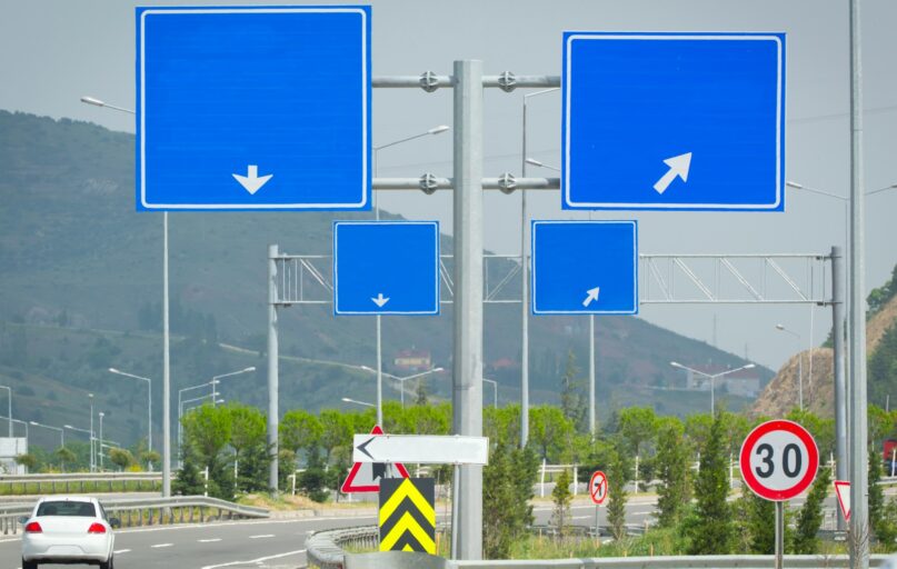 Several blue road signs with arrows on a pole.