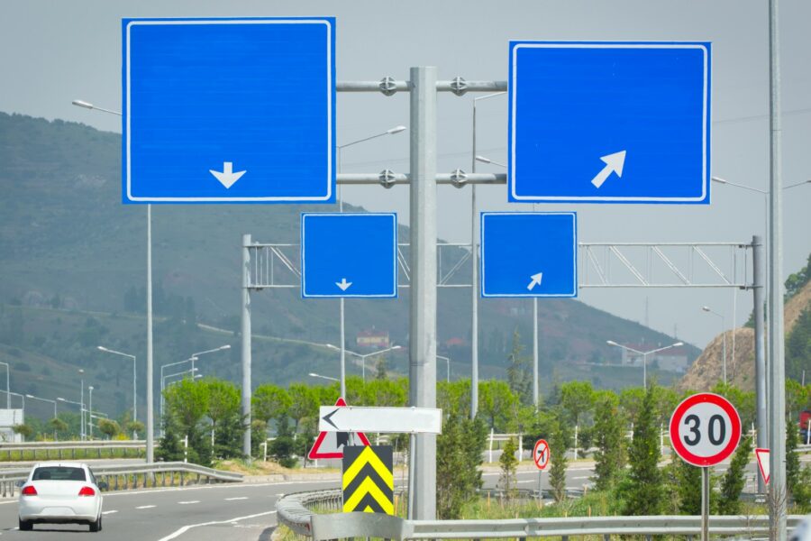 Several blue road signs with arrows on a pole.