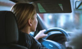 a woman sitting in a car with a steering wheel
