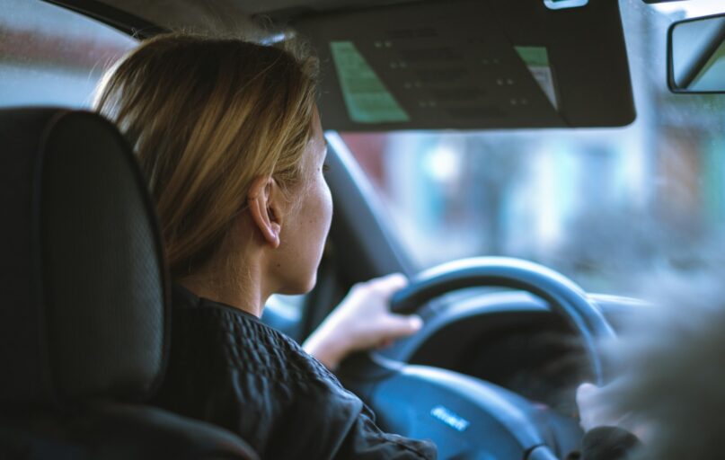 a woman sitting in a car with a steering wheel