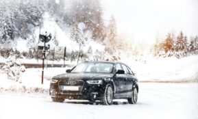 a black car driving down a snow covered road