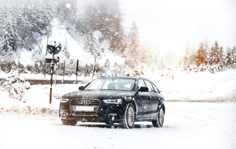 a black car driving down a snow covered road