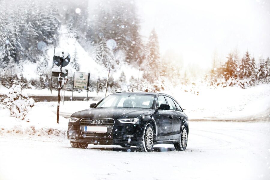 a black car driving down a snow covered road