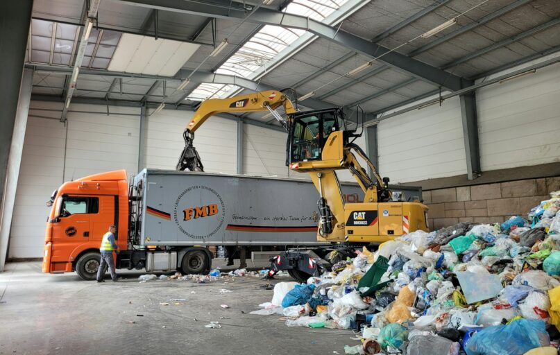 a large truck with a load of trash in a warehouse