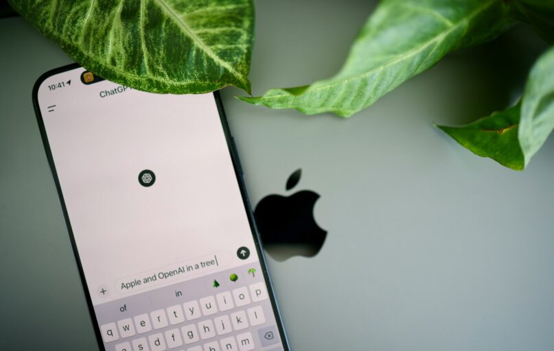 a cell phone sitting next to a green leaf