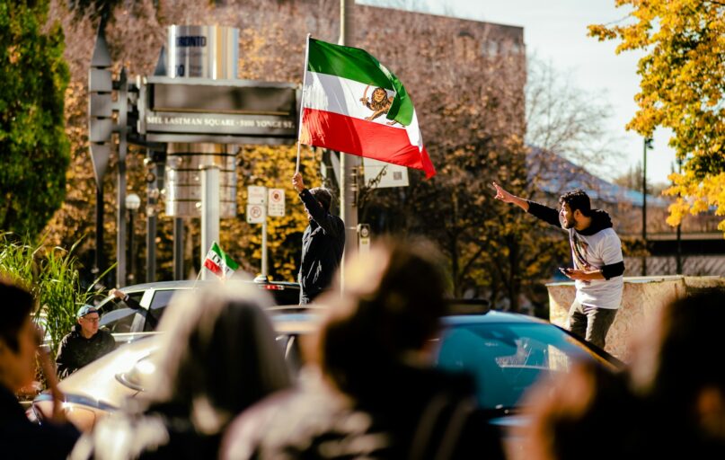 a group of people on a street with a person holding a flag