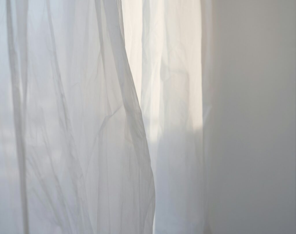 a white curtain with a cat sitting on top of it