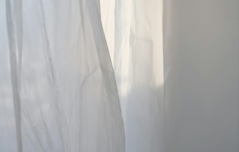 a white curtain with a cat sitting on top of it