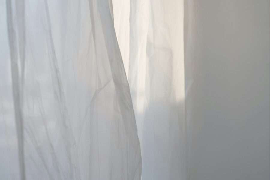 a white curtain with a cat sitting on top of it