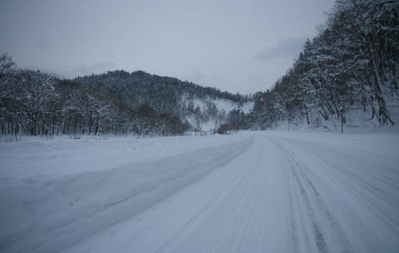 a snow covered road in the middle of a forest