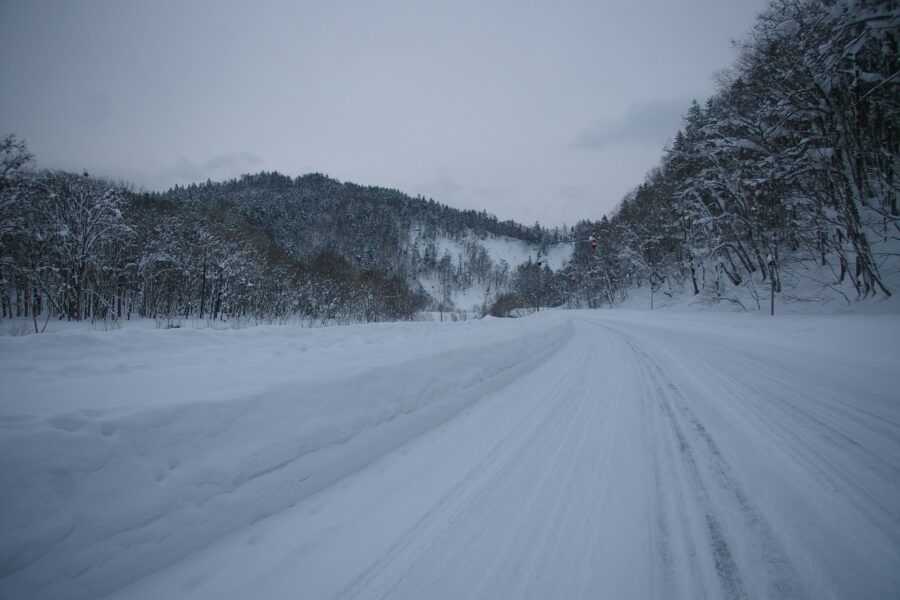 a snow covered road in the middle of a forest
