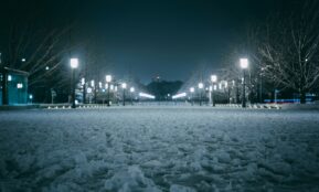 a snow covered park at night with street lights