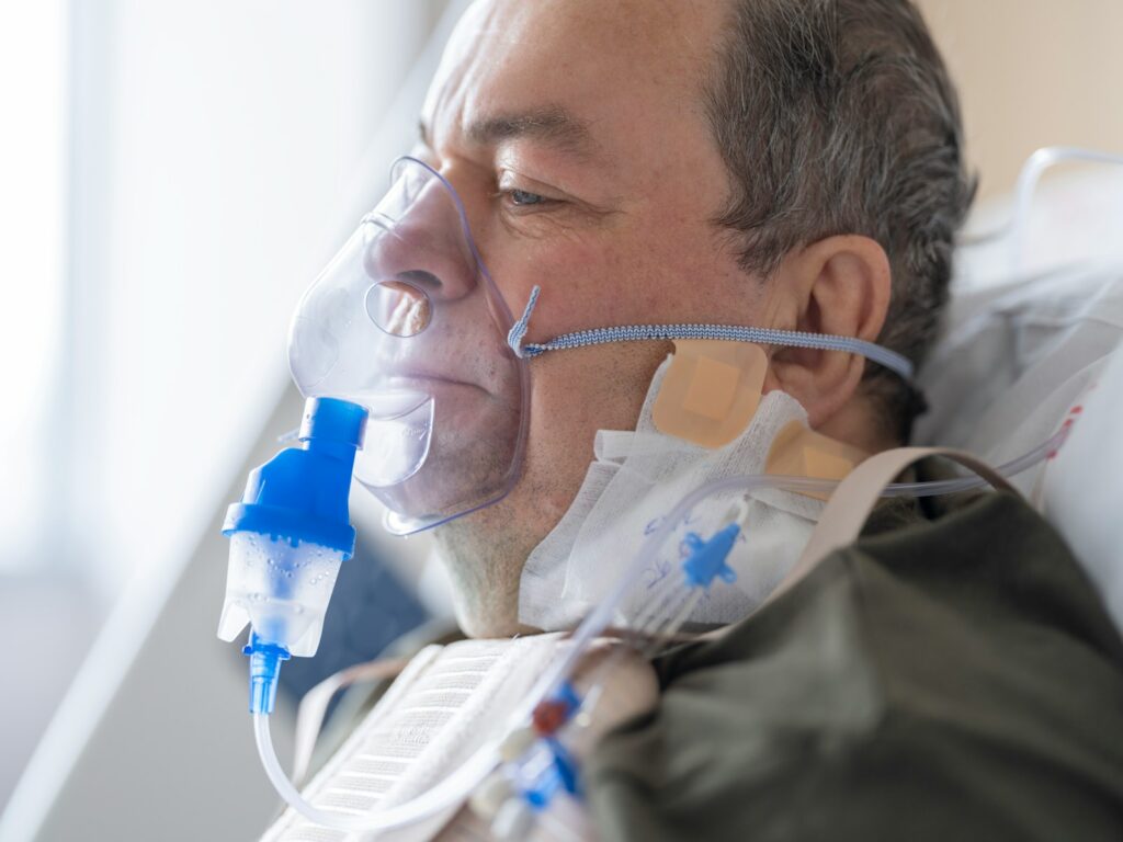 a man laying in a hospital bed with an oxygen tube attached to his face