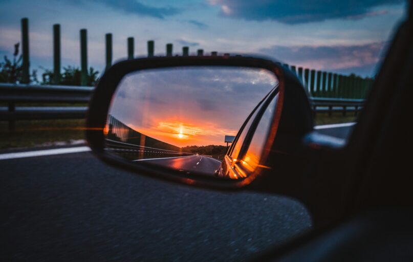 a rear view mirror reflecting a sunset in the side view mirror