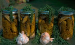 white garlic and green vegetable in clear glass jar