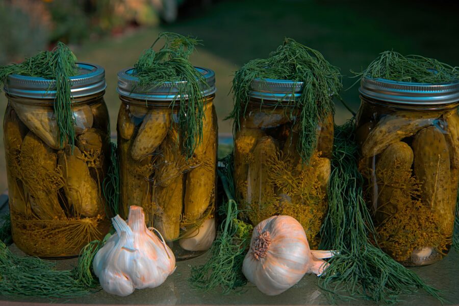 white garlic and green vegetable in clear glass jar