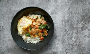 a black plate topped with rice and meat