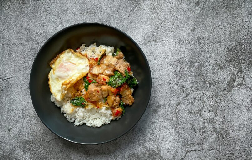 a black plate topped with rice and meat