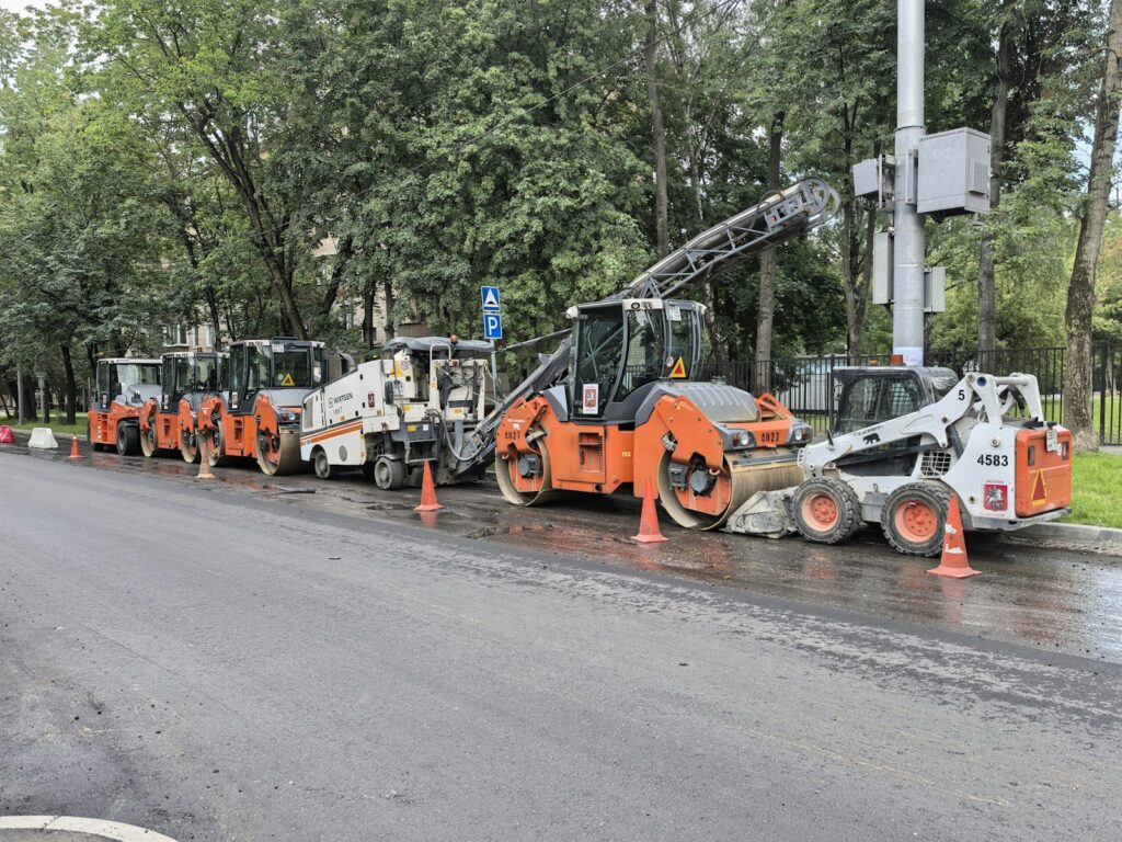 Road construction equipment lined up on wet asphalt