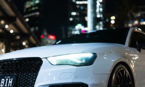 A white car is parked in the city at night.