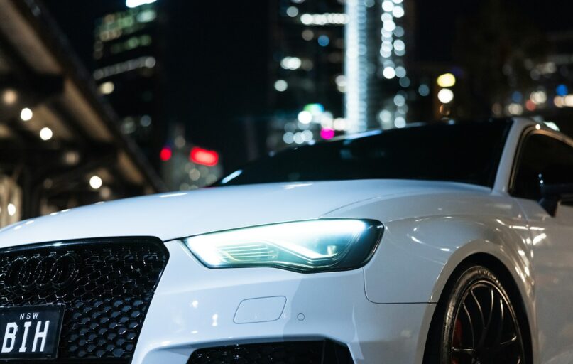 A white car is parked in the city at night.