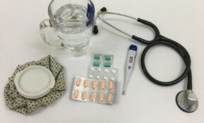 black and silver stethoscope beside clear glass mug