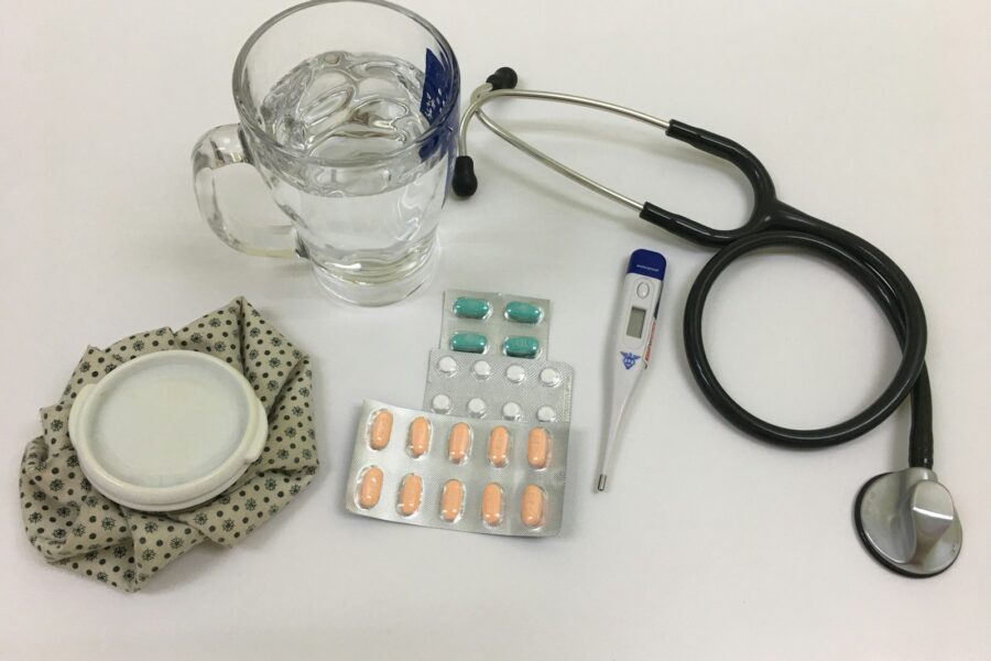 black and silver stethoscope beside clear glass mug