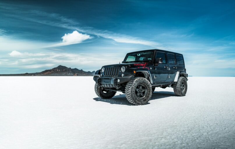 black jeep wrangler on snow covered field under blue sky during daytime