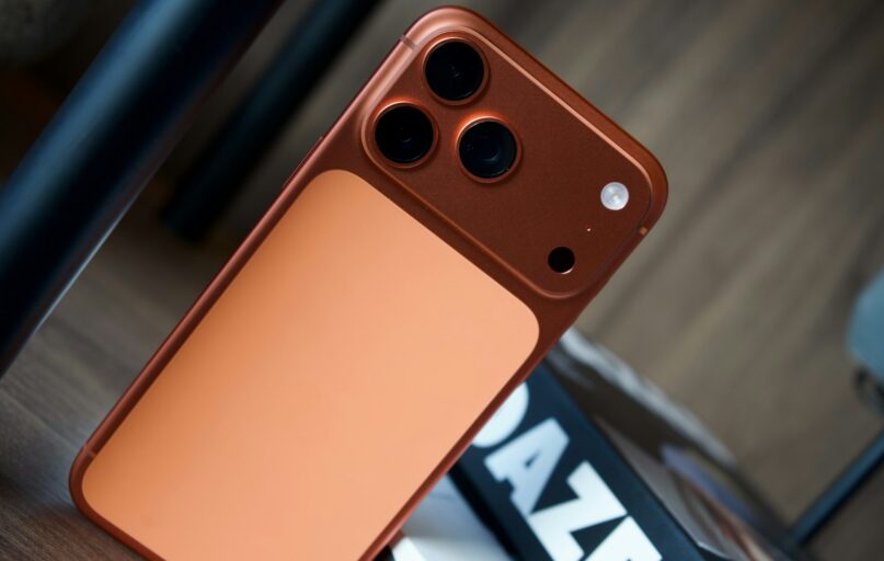 Close-up of a copper-colored smartphone with three cameras.
