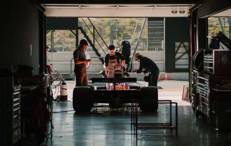 a group of people standing around a car in a garage