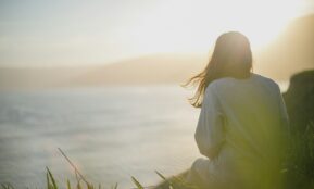 woman wearing gray long-sleeved shirt facing the sea