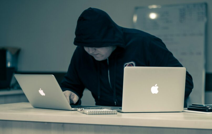 man in black hoodie using macbook