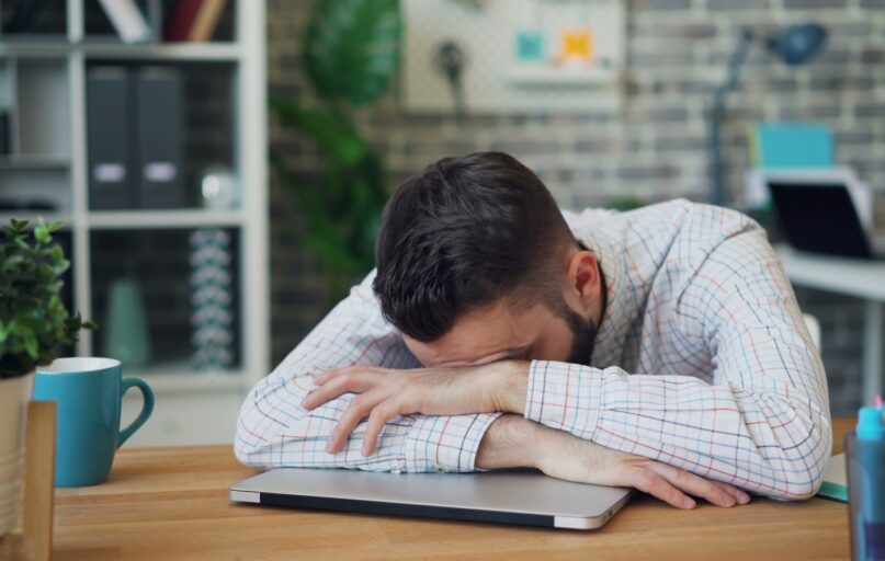 a man sitting at a desk with his head in his hands