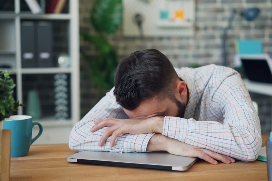 a man sitting at a desk with his head in his hands