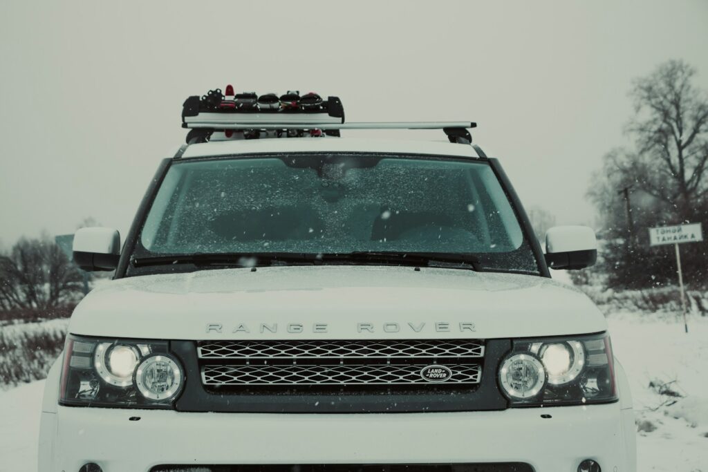 A white land rover is parked in the snow