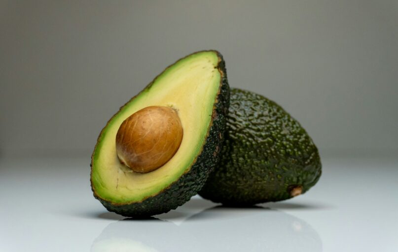 an avocado cut in half on a white surface