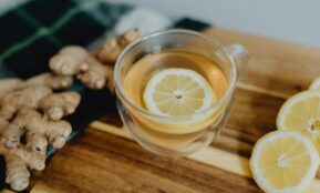 a cup of tea with lemon and ginger on a cutting board
