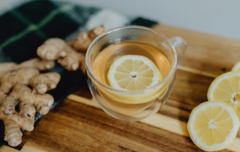 a cup of tea with lemon and ginger on a cutting board