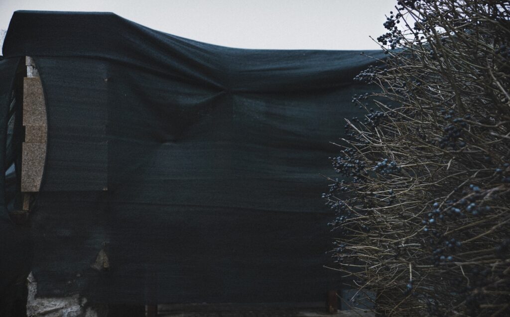 A horse covered in a black tarp in a field
