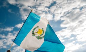 blue and white flag under blue and white sunny cloudy sky during daytime