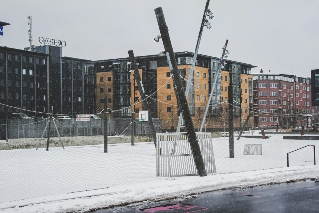 A snowy playground scene in an urban area.