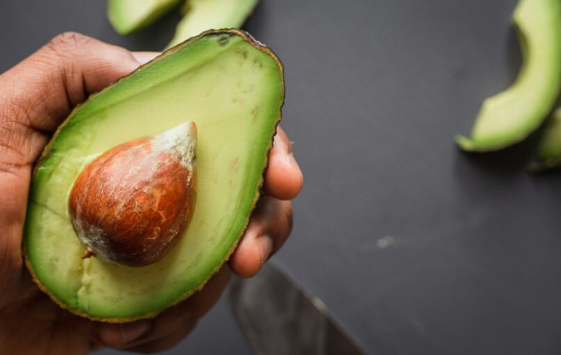 person holding green and brown sliced fruit