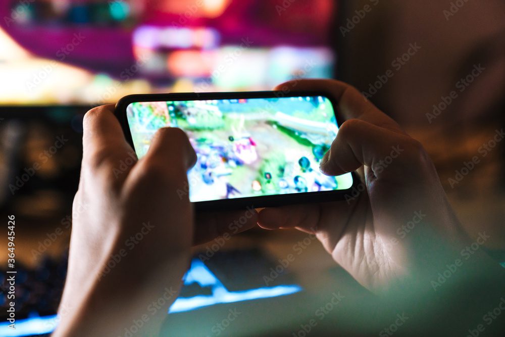Image closeup of focused man playing video game on mobile phone
