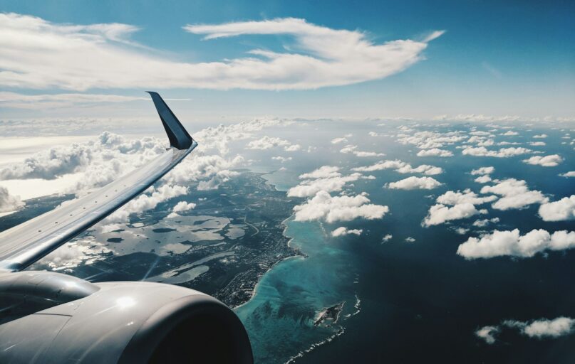 photo of airplane wing under blue sky at daytime
